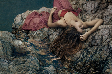 beautiful young woman in red dress laying down in water