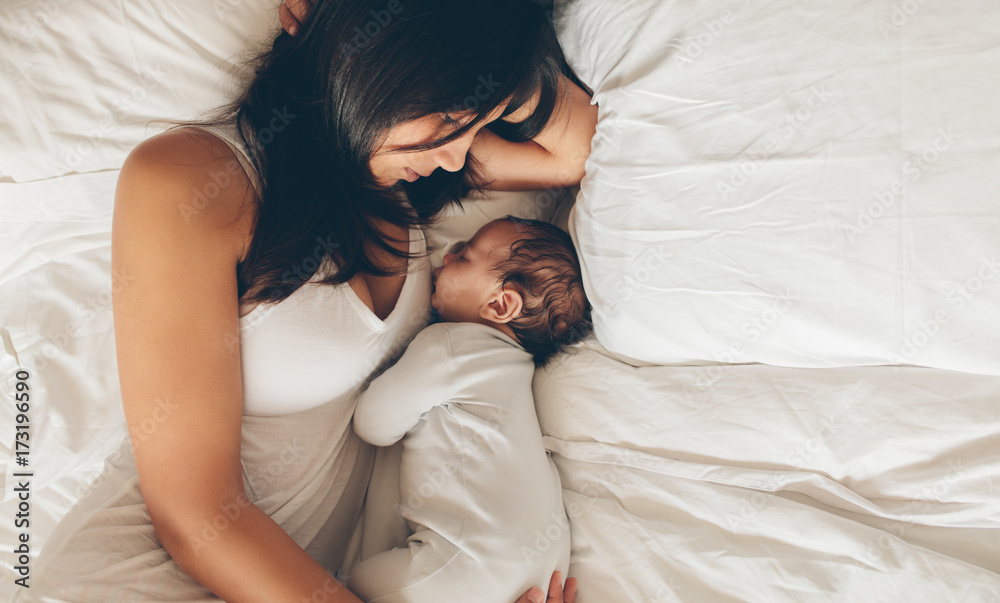 Mother and son sleeping together on bed - obrazy, fototapety, plakaty 