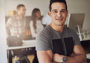 Young businessman with arms crossed in office