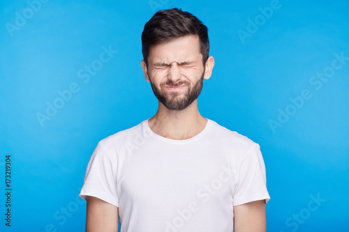 Fotografía Close-up of childish Caucasian student male with brunette hair blowing his cheeks bursting out laughing having joy squinting
