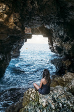 Woman Sitting On Rock In Sea Cave