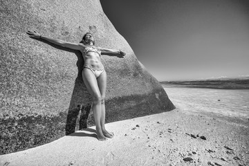 Wall Mural - Beautiful woman leaning on a rock in Seychelles