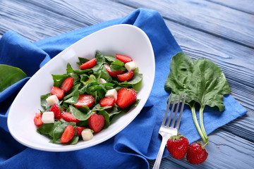 Wall Mural - Plate with strawberry spinach salad on wooden table