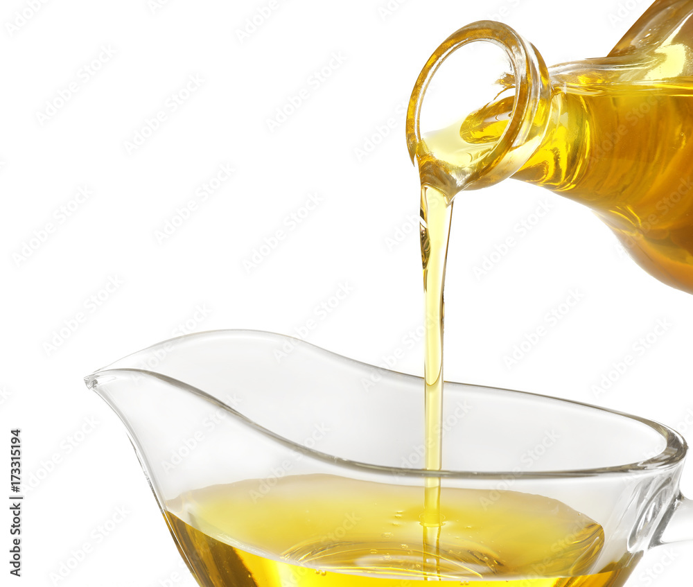 Pouring cooking oil into gravy boat on white background