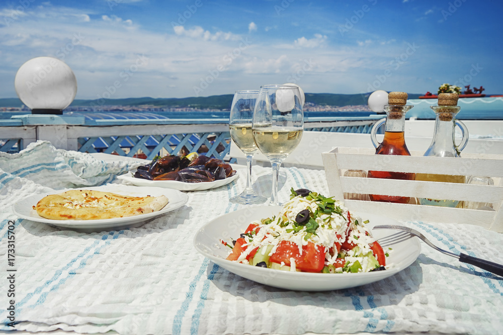 Plates with exotic salad, flatbread and mussels on table in open air restaurant