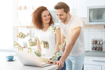 Poster - Happy young couple with laptop in kitchen