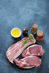 Fresh uncooked bacon and pork chops with seasonings, high angle view with space, vertical shot