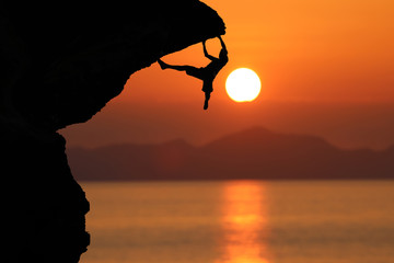 Silhouette of climber on a cliff against beautiful red sky sunset