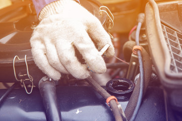 gloves mechanic checks the engine oil of a car