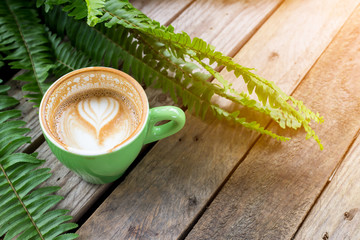 Wall Mural - coffee cup on wood table with fern leaf