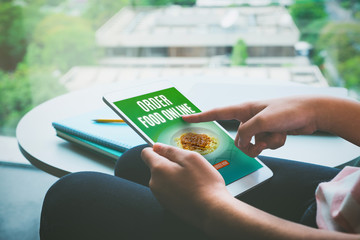 Poster - Close up hand of woman sitting and touch to order food online on tablet computer in home,modern restaurant service concept, Vintage filter
