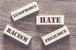 Hate, xenophobia, racism and prejudice words written with tiles on a wooden table. Social issues concept