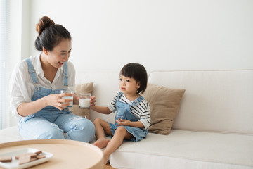 Wall Mural - Happy family of asian mom is drinking milk with her cute daughter in the morning at home