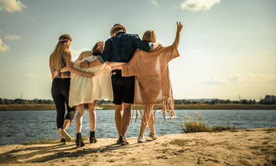 Wall Mural - Group of happy friends walking on beach, fashion styled