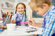 © Seventyfour - Portrait of adorable little girl smiling happily while enjoying art and craft lesson in pre school working together with boy