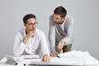 © WHstudio Leushin N - Two design workers brainstrom together: young attractive male tries to persuade his serious boss to make changes in construction plan, shows some defects, wants improvement or takes useful advice