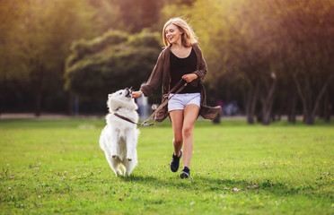 Pretty girl playing and running with samoyed dog at the park