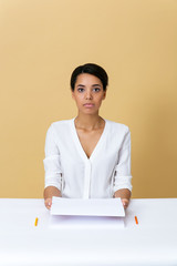 Young woman at the table holding a white paper