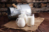 A jug of milk and glass of milk on a wooden table