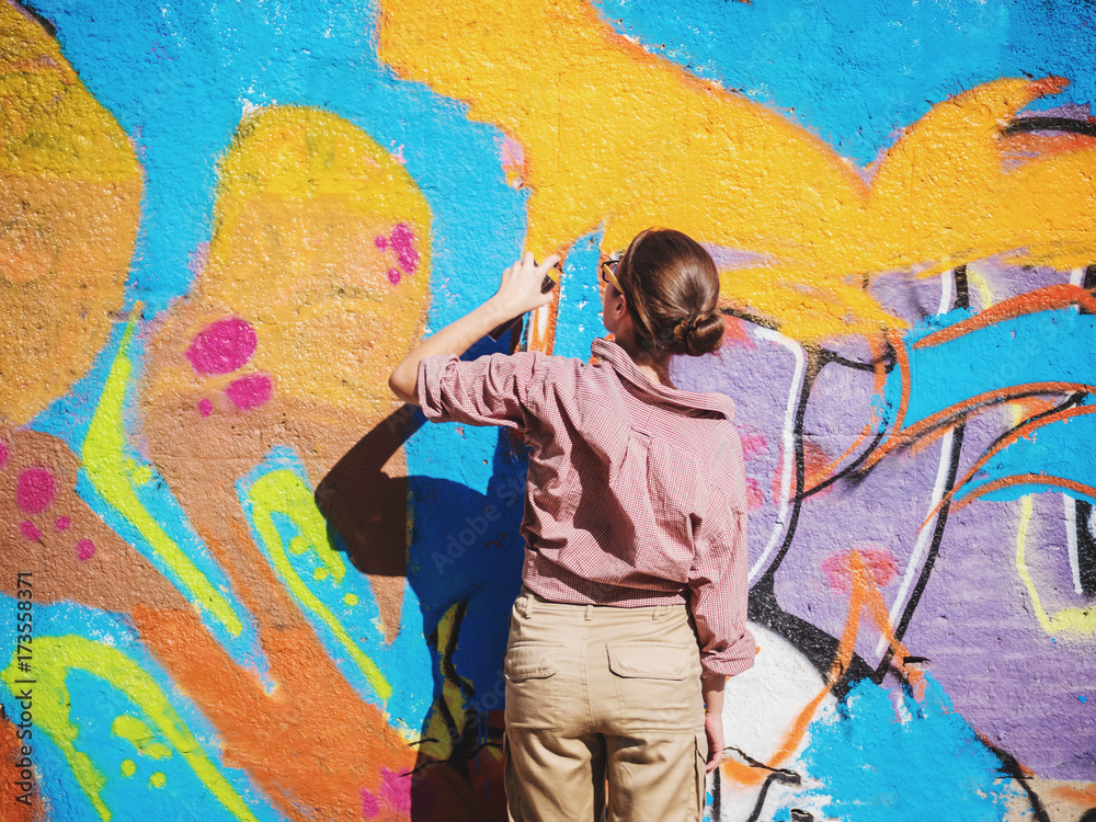 Beautiful Young Girl making a colorful graffiti with aerosol spray on ...