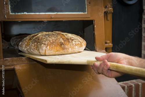 Zdjęcie XXL Baker zabranie chleba na jedzenie z drewnianą łopatą z tradycyjnego pieca piekarniczego