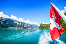 Switzerland National Flag At Cruise Boat's Rear End With Beautiful Summer View Of Swiss Natural Alps, Lake And Clear Blue Sky As A Background, Lake Brienz, Interlaken-Oberhasil, Bern, Switzerland.