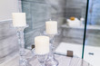 Closeup of staging modern stone grey tiled bathroom in model home, apartment or house with candles, towels, pouf and soap