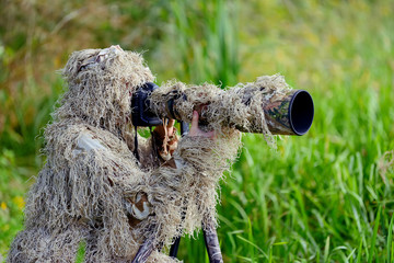 Wall Mural - Camouflage wildlife photographer in the ghillie suit