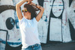 © Alena Ozerova - Model wearing plain tshirt and sunglasses posing over street wall