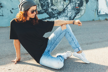 Model wearing plain tshirt and sunglasses posing over street wall