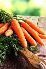 Fresh organic carrots with green leaves on wooden background. Ve