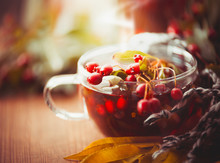 Cup Of Autumn Tea With Red Berries Of Hawthorn And Fall Leaves, Front View