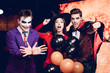 © VadimGuzhva - Two guys in Halloween costumes and a girl in a witch costume posing with inflatable balloons at a nightclub