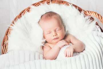 sleeping newborn baby in a wrap on white blanket.
