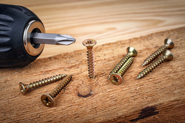 cordless drill and large screws on a wood background