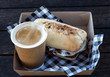 Bacon and egg breakfast ciabatta roll with take away coffee with checkered serviettes in box