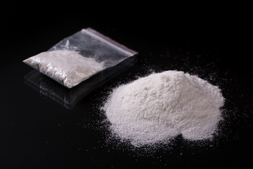 Wall Mural - Cocaine in plastic packet on black background