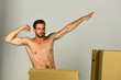Sexuality and moving in concept: naked superhero among boxes