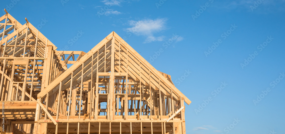 Close-up of gables roof on stick built home under construction and blue sky in Humble, Texas, USA. New build roof with wooden truss, post and beam framework. Timber frame house, real estate. Panorama - obrazy, fototapety, plakaty 