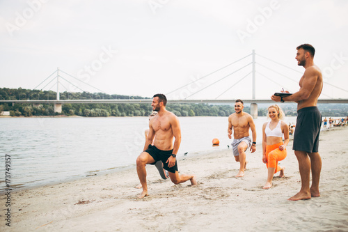 Zdjęcie XXL Grupują młodych atrakcyjnych ludzi ma zabawę na plaży i robi niektóre sprawności fizycznej trening.