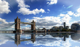 Fototapeta Londyn - Tower Bridge spanning the River Thames with a dramatic blue cloudy sky and good water reflection