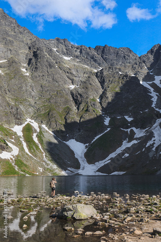 Lonely tourist taking pictures near the Black pond in High Tatra mountain in Poland Poster