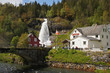 Steinsdalsfossen waterfall in the river of Steine - scenic landscape with cascade surounded by mountains and traditional norvegian, scandinavian houses