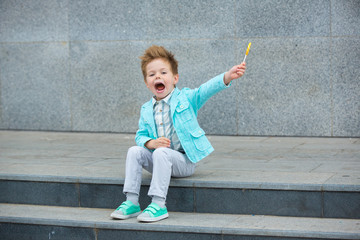 Wall Mural - Fashion kid with lollipop near gray wall