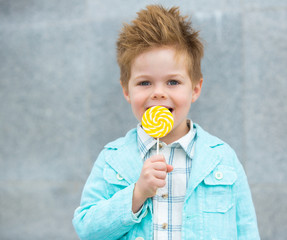 Wall Mural - Fashion kid with lollipop near gray wall