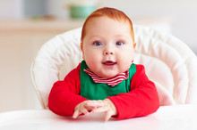 Portrait Of Cute Infant Baby Boy In Elf Costume Sitting In Highchair
