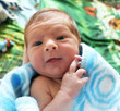 Portrait of newborn smiling baby in blue blanket.