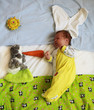Cute newborn baby in bunny costume feeding bunny toy with a carrot