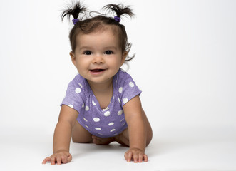 smiling, infant girl crawling on white background dressed in purple, polka dot onesie