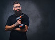 © Fxquadro - A man holds a drill over grey background.